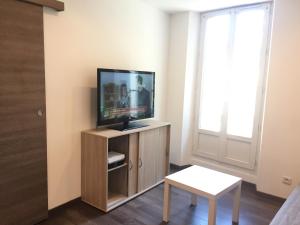 a living room with a flat screen tv on a cabinet at T2 Hyper centre clim,WIFI in Hyères