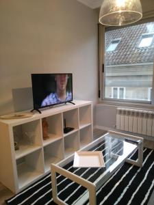 uma sala de estar com uma televisão de ecrã plano num armário branco em Torre Center em Santiago de Compostela