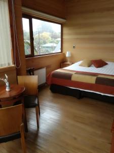 1 dormitorio con cama, ventana y mesa en Puerto Chico Hotel, en Puerto Varas