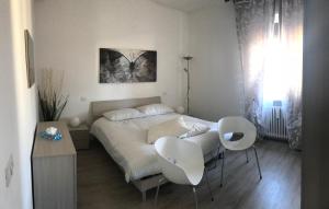 a bedroom with a bed and two white chairs at Appartamenti Giada in Verona