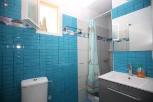 a blue tiled bathroom with a toilet and a sink at Pelagos in Stafylos