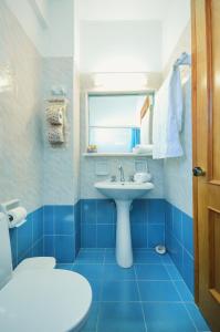 ein blaues Bad mit einem Waschbecken und einem Fenster in der Unterkunft Skarmoutsos Studios in Aliko Beach