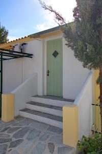 a green door on a white building with stairs at Pelagos in Stafylos