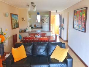 um sofá de couro preto numa sala de estar com almofadas amarelas em Condominio ILIMAY em Las Cruces