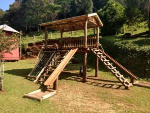 a wooden playground with a slide in the grass at Hotel Pousada Por do Sol in Protásio Alves