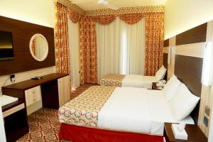 a hotel room with two beds and a desk at Deema Hotel in Dubai