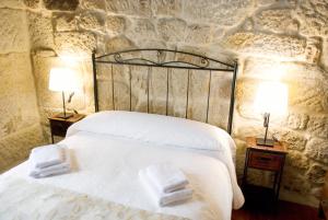 a bedroom with a white bed with two lamps on tables at A Lareira De Allariz in Allariz