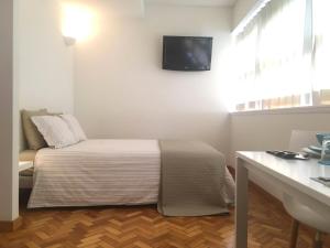 a bedroom with a bed and a tv on the wall at Studios Baixa Downtown Porto in Porto
