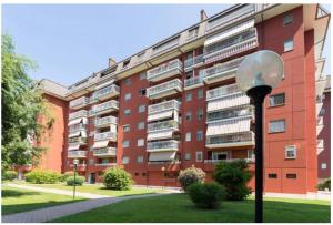 duży czerwony budynek apartamentowy z światłem ulicznym przed nim w obiekcie Apartment Forum 2 w mieście Assago