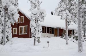 a house covered in snow with trees in the foreground at Villa Kyyhkynen in Rovaniemi