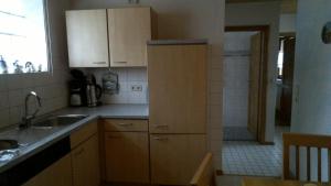 eine Küche mit Holzschränken, einem Waschbecken und einer Dusche in der Unterkunft Apartment Meyerhof in Schwanau