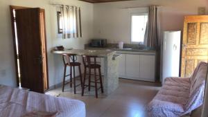 cocina con encimera y taburetes en una habitación en Baleia Branca Chalé, en Porto Belo