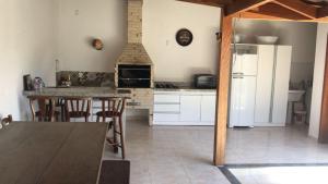 a kitchen with a table and a white refrigerator at Baleia Branca Chalé in Porto Belo