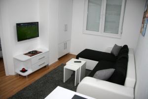 a white living room with a black couch and a tv at Central DeLuxe Apartments Ohrid in Ohrid