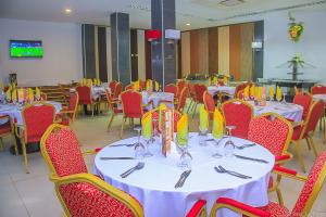 a dining room with white tables and red chairs at Hotel LAFORGE in Abidjan