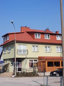 un gran edificio con techo rojo en una calle en Roadway en Kielce