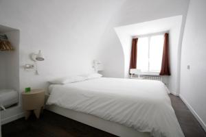 トリノにあるAppartamento Quadrilatero Romanoの白いベッドルーム(ベッド1台、窓付)