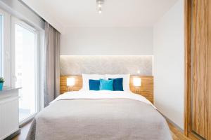 a bedroom with a large bed with blue pillows at ActivPark Apartments in Katowice