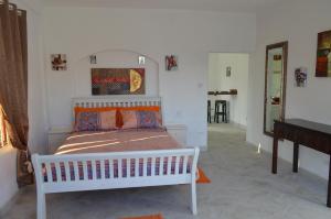 Un dormitorio con una cama blanca en una habitación. en Frangipani Apartment, en Christ Church