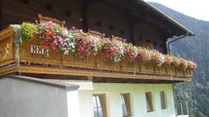 einen Balkon mit Blumen an der Seite eines Gebäudes in der Unterkunft Ferienwohnungen Niederarnigerhof Familie Bauernfeind in Kals am Großglockner