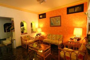 ein Wohnzimmer mit orangefarbenen Wänden und Stühlen und Tischen in der Unterkunft Hotel Plaza Crystal in Xalapa
