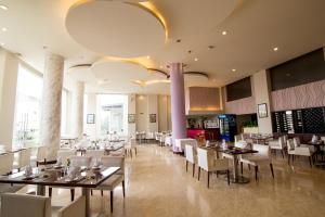 uma sala de jantar com mesas e cadeiras brancas em TTC Hotel - Ngoc Lan em Da Lat