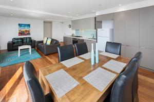 a dining room with a table and chairs and a kitchen at Pier Point 105 in Geelong