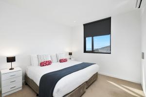 a white bedroom with a large bed and a window at Pier Point 105 in Geelong