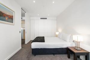 a bedroom with a bed and a table with a lamp at Edgewater 207 in Geelong