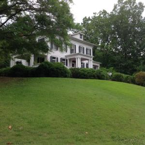 ein weißes Haus auf einem Grashügel in der Unterkunft Springwood Inn in Anniston