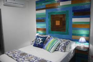 een slaapkamer met een bed met kussens en een kleurrijke muur bij Olas Del Caribe in San Andrés