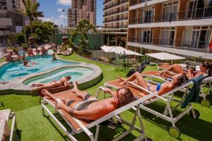 um grupo de pessoas deitadas em espreguiçadeiras numa piscina em Bunk Surfers Paradise International Backpacker Hostel em Gold Coast