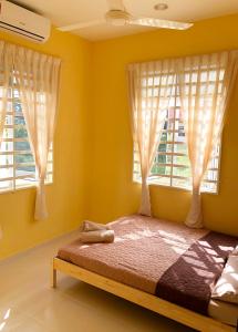 a bedroom with yellow walls and a bed with windows at Twin Homestay D in Kuala Terengganu