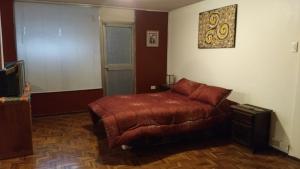 1 dormitorio con cama marrón y sofá en Apartamento independiente a 6 minutos de Mall el Jardín, en Quito