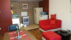 a living room with a red chair and a kitchen at Apartamento independiente a 6 minutos de Mall el Jardín in Quito