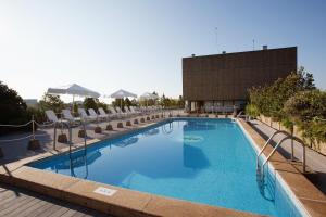 a large swimming pool with chairs and a building at Hotel Palafox in Zaragoza