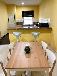 Una cocina con una mesa de madera y sillas blancas. en Twin Homestay C, en Kuala Terengganu