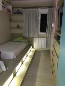 a small bedroom with a bed with lights in it at Lindo apartamento no centro de Canela in Canela