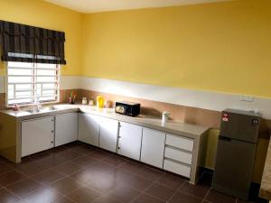 a kitchen with white cabinets and a sink and a refrigerator at Twin Homestay D in Kuala Terengganu