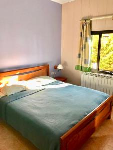 a bedroom with a bed with a blue comforter and a window at Stone Chalets in Fārayyā +137 photos