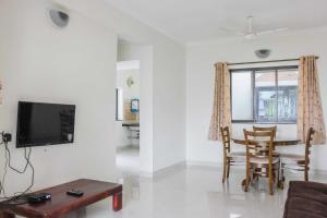a living room with a tv and a table and chairs at Sun & Sand in Candolim
