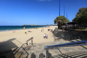 a beach with people sitting on chairs and umbrellas at Caribbean Resort in Mooloolaba