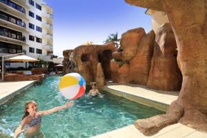 Caribbean Resort في مولولابا: فتاة صغيرة تلعب مع كرة الشاطئ في حمام السباحة