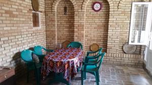 a table and chairs in a room with a brick wall at Payraviy in Bukhara