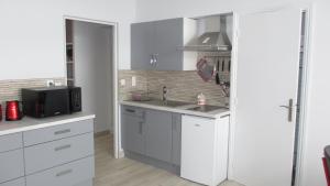 a kitchen with white cabinets and a sink and a microwave at Le Gîte les Châtaignes in Volvic +19 photos