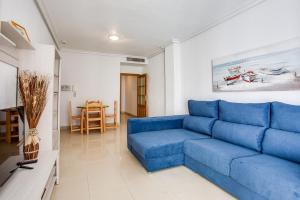een blauwe bank in een woonkamer met een tafel bij Los Locas First Line Apartments in Torrevieja