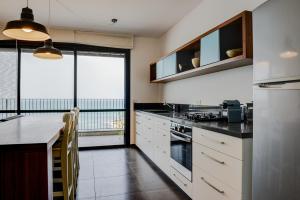 a kitchen with white cabinets and a large window at Beautiful Apartment on The First Line of The Sea in Haifa
