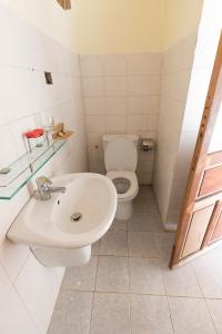 a white bathroom with a toilet and a sink at Tam Thanh Natural Beach Resort in Tam Ky