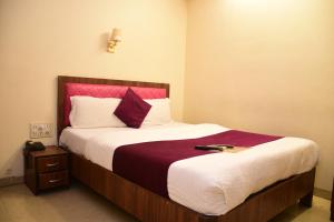 a bedroom with a large bed with a red headboard at Hotel K.C Residency in Mumbai