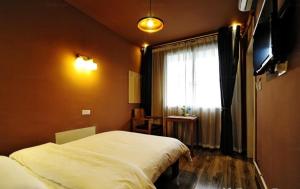 a bedroom with two beds and a television and a window at Shu Hostel in Guiyang